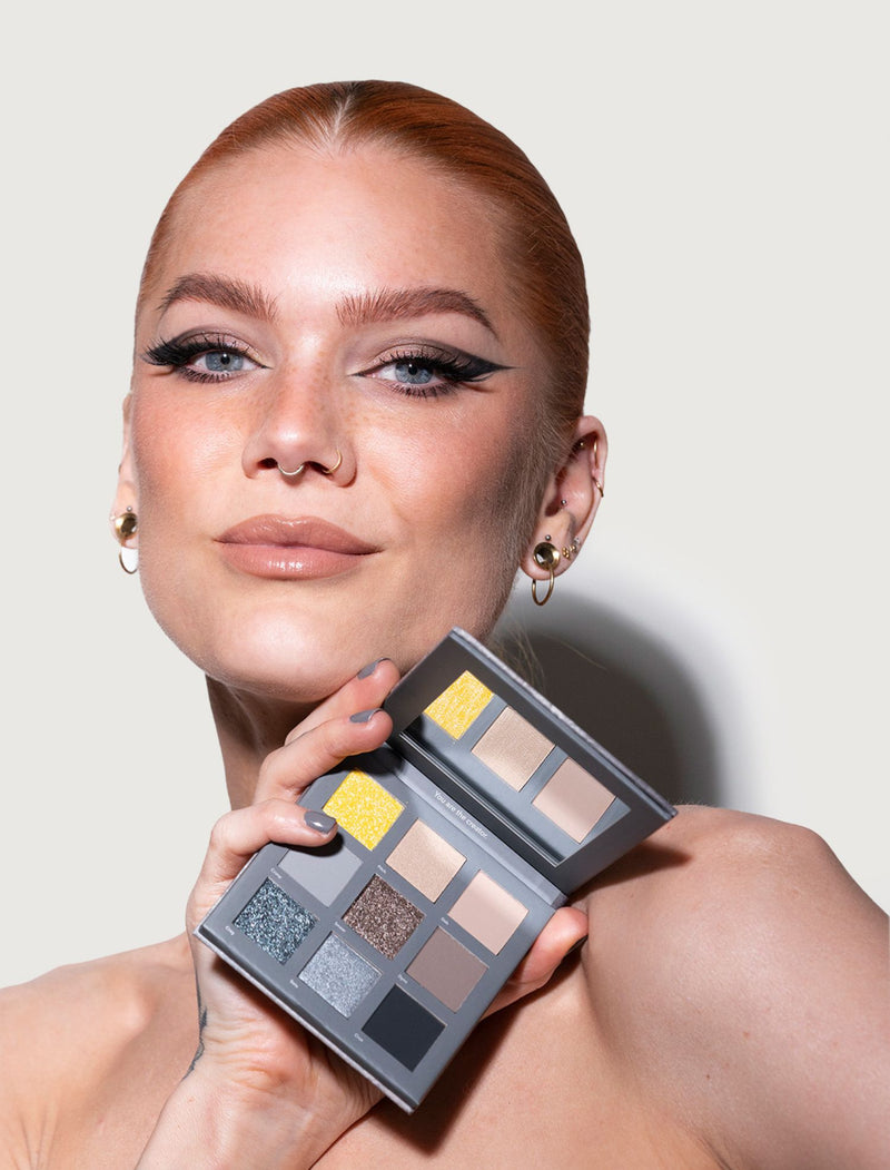 a woman holding a palette of makeup in front of her face